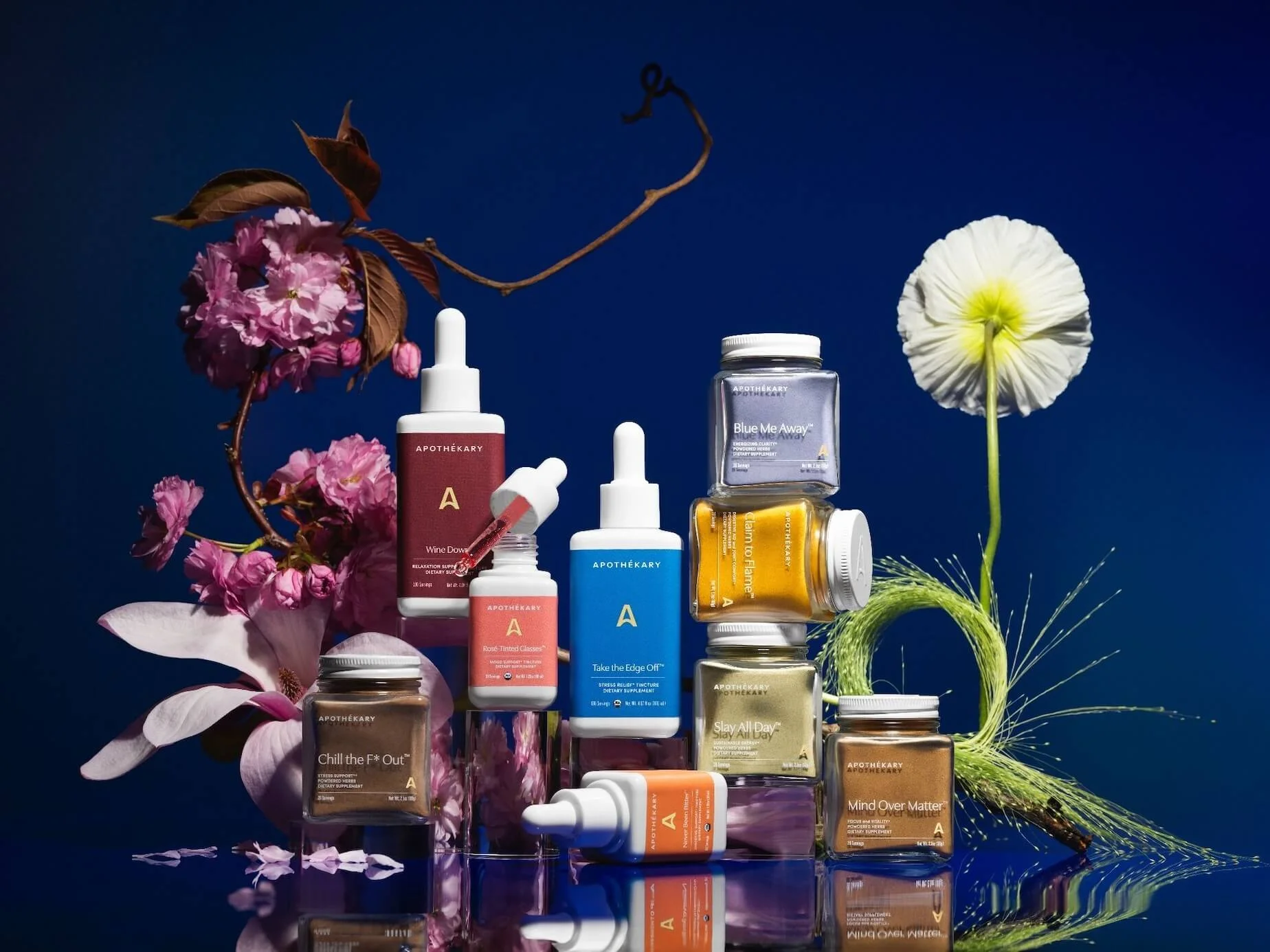 Collection of Apothékary products and flowers on a blue background